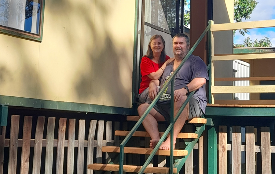 woman and man sitting on the stairs to the front deck of their Macleay Island home