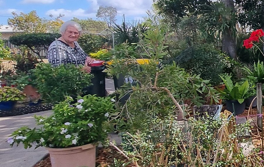 Woman showcasing transformed industrial site into backyard garden oasis in social housing complex