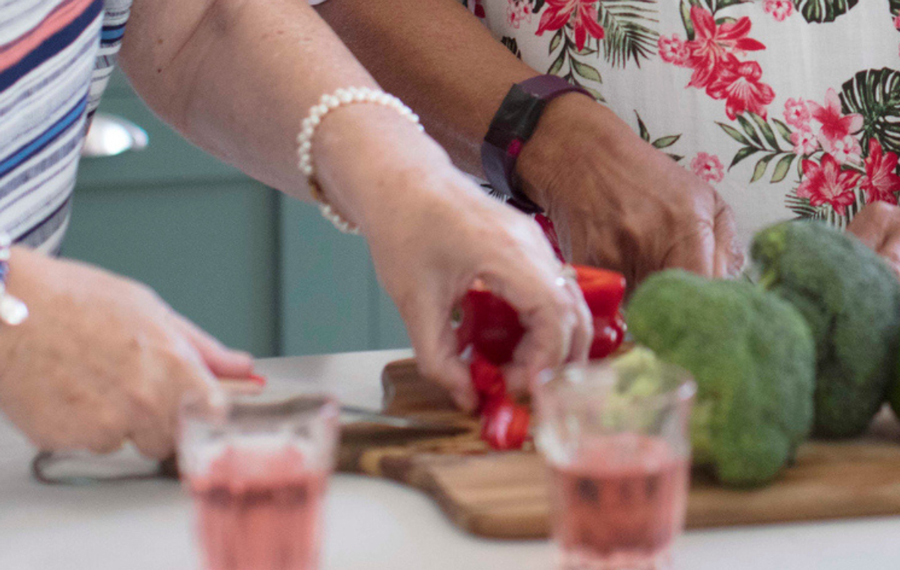 Woman cutting capsicum to prepare meals for a potluck dinner