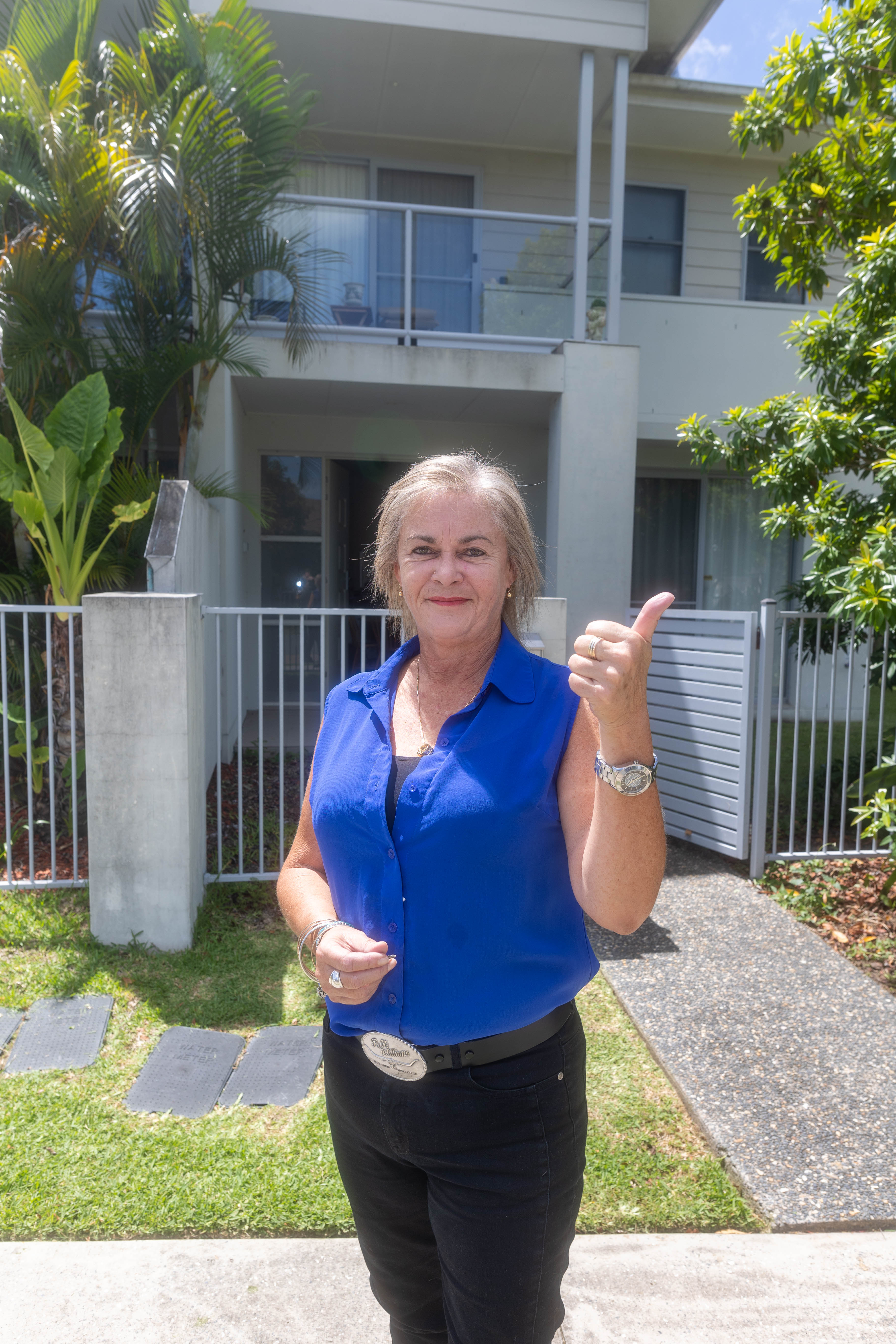 Kim standing outside a townhouse complex giving the thumbs up